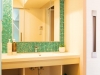 洗面台の鏡まわりはグリーンのガラスモザイクタイルで爽やかさと明るさを演出。　　